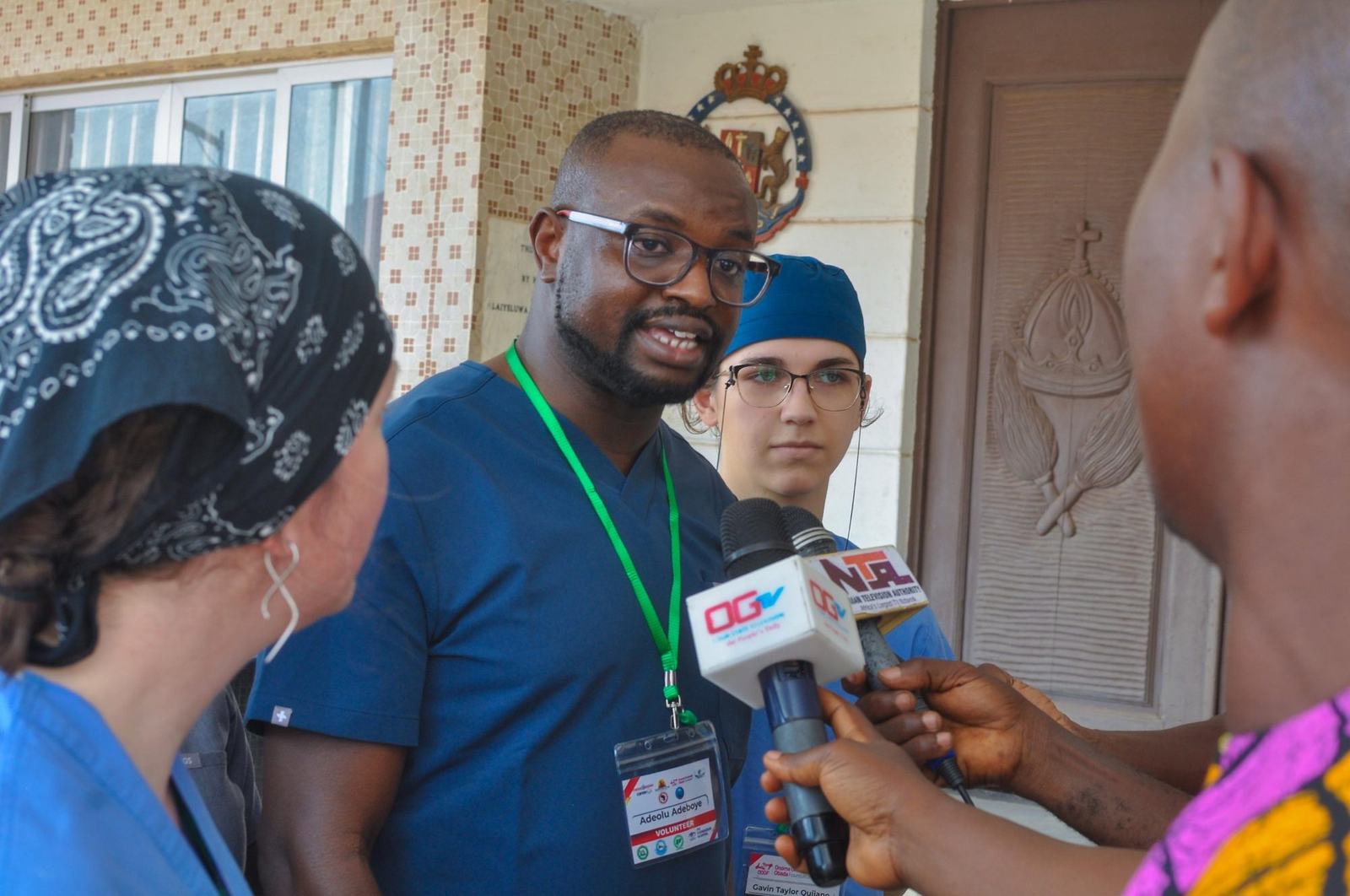 Dr. Adeboye in blue scrubs giving a television interview