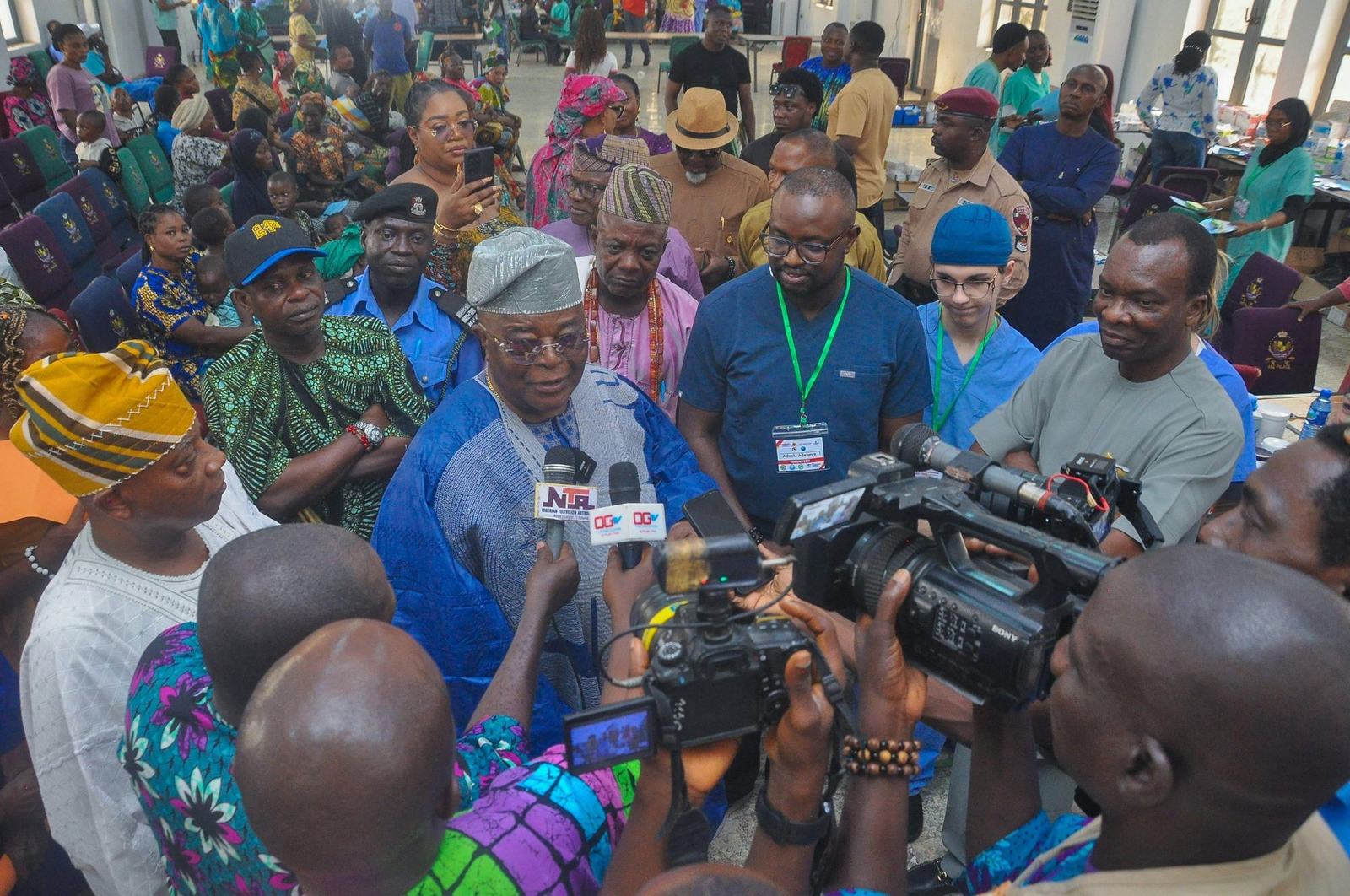Dr. Adeboye speaking with television reporters in front of a large crowd